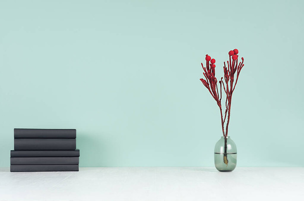 Minimalistic style home workplace with black books, red branch on green mint menthe wall and white wood table, copy space. - Фото, зображення