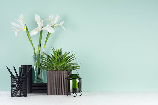 Spring green mint menthe interior of office with black stationery, books, green potted plant of aloe, fresh white iris bouquet, candlestick on soft light white wood board. - Valokuva, kuva