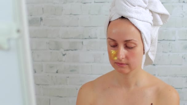 Vrouw die gouden hydrogel masker op gezicht aanbrengt - Video
