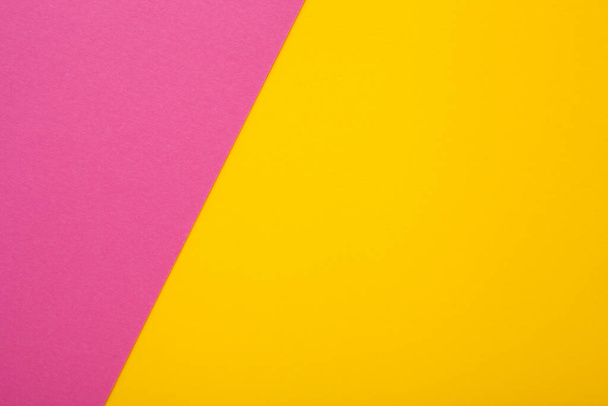 Ροζ και κίτρινο χαρτί ως φόντο. Δίχρωμο φωτεινό χαρτί υφή, κορυφαία προβολή με θέση για κείμενο - Φωτογραφία, εικόνα