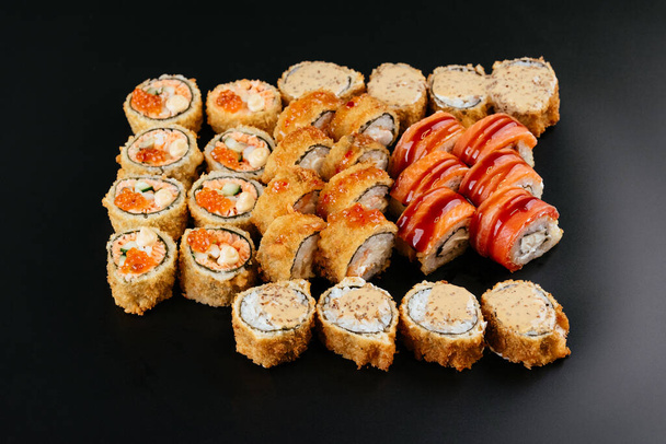 színes különböző sushi tekercsek szett lazac hal, garnélarák és füstölt angolna krémsajttal fekete tálcán - Fotó, kép