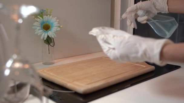 Vrouwelijke handen in witte handschoenen ontsmetten keukenaanrecht door thuis te sproeien en af te vegen, het voorkomen van virus van besmette oppervlakken, corona virus covid-19, antibacteriële product, wijnglazen schotels. - Video