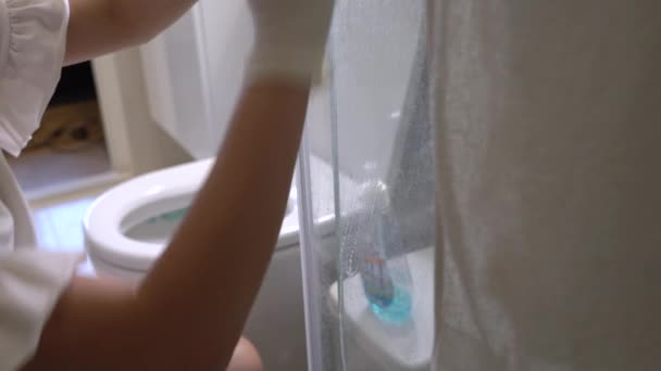 Női szobalány fehér kesztyű takarítás otthoni fürdőszoba üveg ajtó, üveg felület, fertőtlenítő törlőkendők, megakadályozzák a koronavírus covid19, otthoni tisztítás koncepció, megöli baktériumok, permetezés törlése belsejében WC-szobában  - Felvétel, videó