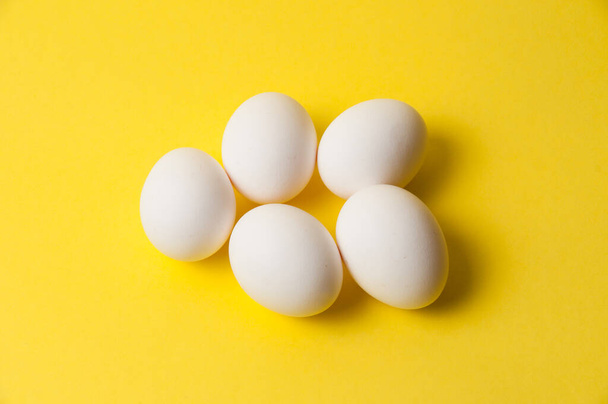 Several chicken eggs on bright yellow background, copy space - Foto, Imagem