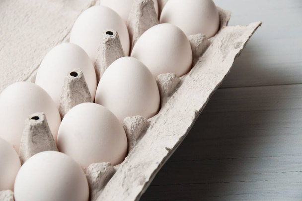 Huevos de pollo blanco en bandeja sobre un fondo de madera claro, espacio para copiar
 - Foto, imagen