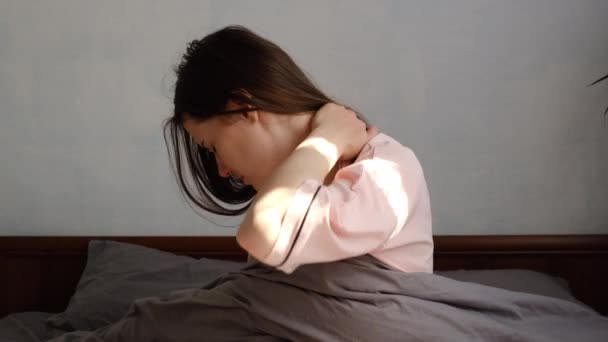 Μπροστά άποψη της αναστατωμένος νεαρή γυναίκα φορούν πιτζάμες αισθάνεται πόνο στο λαιμό το πρωί μετά τον ύπνο, αφυπνίζονται σε κακή ιδιοσυγκρασία έχουν επώδυνο ξαφνικό πόνο ή δυσκαμψία. Έννοια της ινομυαλγίας - Πλάνα, βίντεο