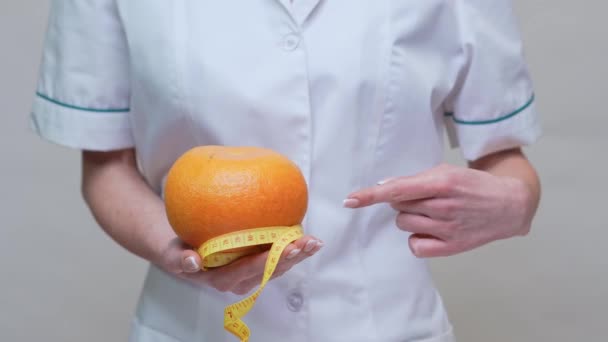 nutritionist doctor healthy lifestyle concept - holding organic grapefruit fruit and measuring tape - Filmagem, Vídeo