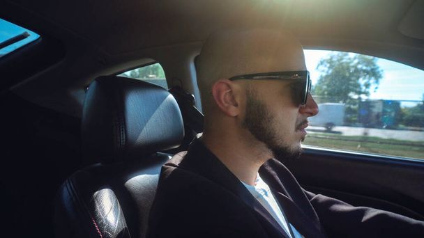 sexy young man drivin a car in black sunglasses - 写真・画像
