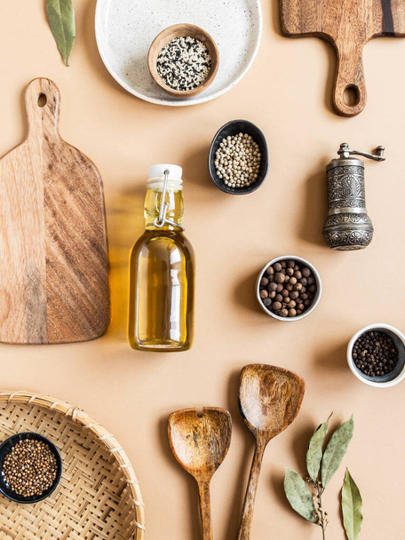 Flat lay of small bowls various dry spices, wood kitchen utensils, olive oil in glass bottle on a beige background. Top view. - Photo, Image
