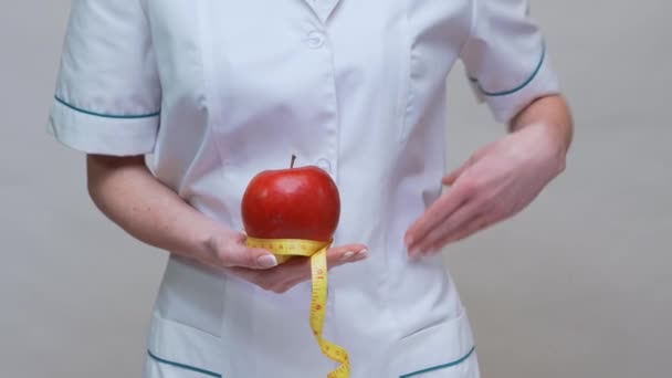 nutritionist doctor healthy lifestyle concept - holding organic red apple and measuring tape - Felvétel, videó