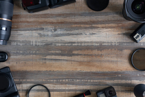 Disposición plana de equipos de fotografía sobre fondo de escritorio de madera: cámara dslr y lente. Concepto de espacio de trabajo del fotógrafo. Copiar espacio, vista superior
 - Foto, Imagen