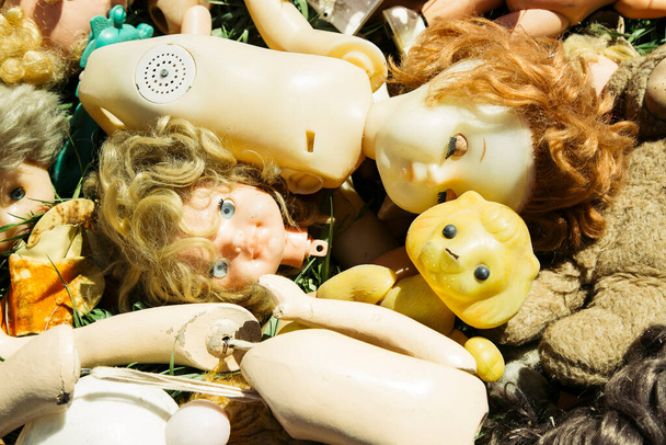 Багато старих ламаних ляльок та іграшок на траві кинуті як сміття
 - Фото, зображення