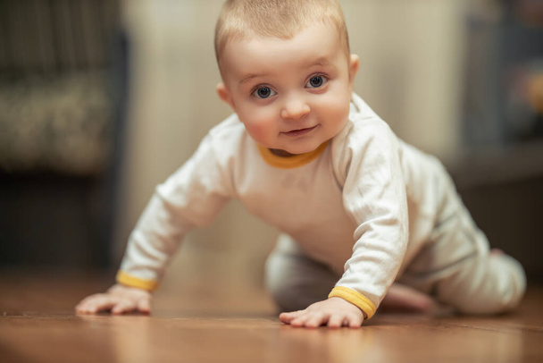 Smiling crawling baby boy at home on floor.Bright portrait of adorable baby. - 写真・画像