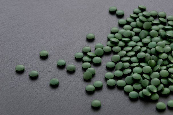 pastillas verdes, tabletas de espirulina en placa de piedra negro
. - Foto, Imagen