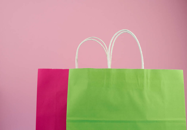 bolsas de papel multicolores vacías para ir de compras y regalos con asas blancas de pie sobre un fondo rosa
 - Foto, imagen