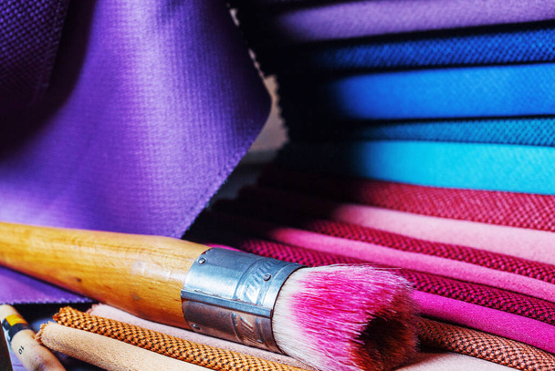 kolorowe tkaniny leżą na kolorowej pełnej palecie artystki.Kolorowe pędzle i tkaniny. - Zdjęcie, obraz