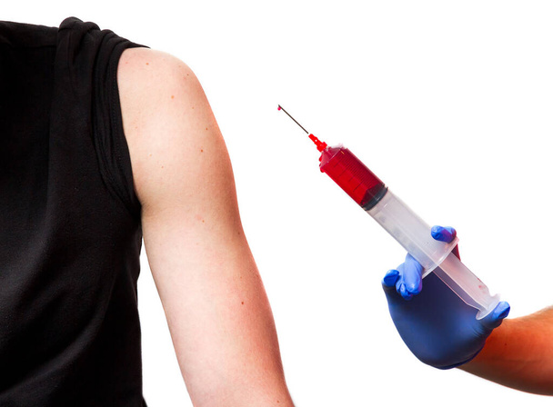 Siringa grande con liquido rosso pronta a vaccinare un braccio o a prelevare sangue
 - Foto, immagini