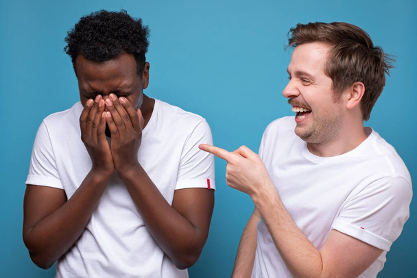 Белый человек смеется над своим другом. Он выиграл спор или соревнование
. - Фото, изображение