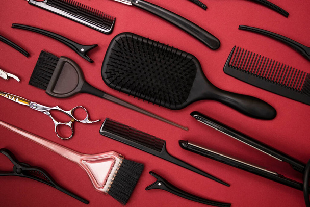 grzebienie i narzędzia fryzjerskie na czerwonym tle widok z góry - Zdjęcie, obraz