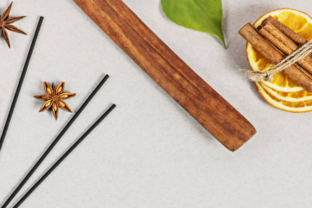 Incense sticks with stand, sliced in orange circles in a wooden bowl and anise star, cinnamon sticks on a gray background.Candle in the form of a flower and a shell.Aromatherapy. Home spa concept - Foto, immagini
