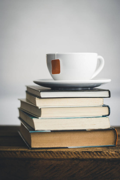 Ένα φλιτζάνι τσάι σε μια στοίβα από βιβλία. Κοντινό πλάνο.  - Φωτογραφία, εικόνα