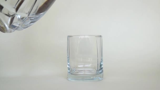 Pour water into a glass glass of vase on a white background - Filmati, video