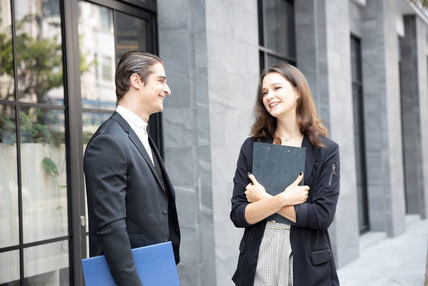 市内のオフィスビルの前に立っている2人の白人ビジネスマンの幸せと笑顔. - 写真・画像