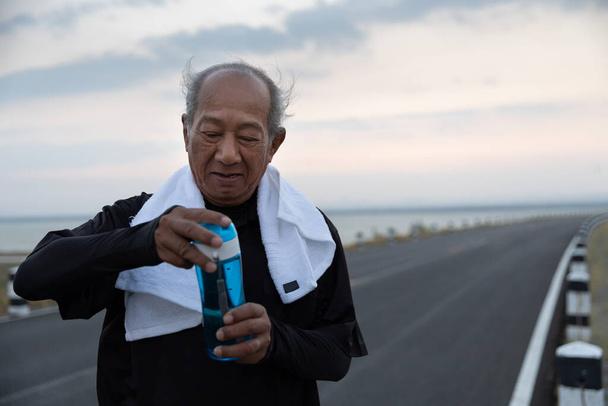 運動後にアジアの高齢者飲料水を閉じます。健康ライフスタイルと運動コンセプト. - 写真・画像