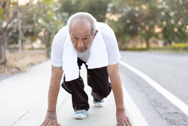 Vue de face asiatique exercice pour personnes âgées. Le doyen en position prêt à courir. Un homme déterminé prêt pour un sprint. mode de vie sain et exercice Start Up Concept
 - Photo, image