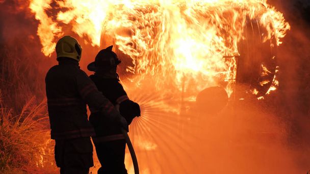 Visão traseira do bombeiro asiático usar terno de proteção contra incêndio. Bombeiro pulverizar água lutando. Emergência, fogo! perto de...
 - Foto, Imagem