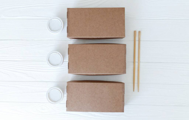 Conjuntos de sushi sobre contenedores eco biodegradables listos para llevar sobre fondo de madera blanca
 - Foto, Imagen