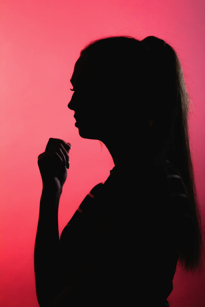 силует збентеженої дівчини на червоному освітленому фоні, невпізнавана жінка стикається з профілем, концептуальними емоціями, стресом
 - Фото, зображення