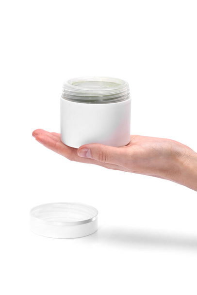 Woman's hand is holding a cosmetics jar with natural vegan green cream isolated on a white background. - Φωτογραφία, εικόνα