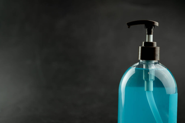Blue hand sanitizer bottle on black background. COVID-19 Coronavirus concept. - Fotoğraf, Görsel