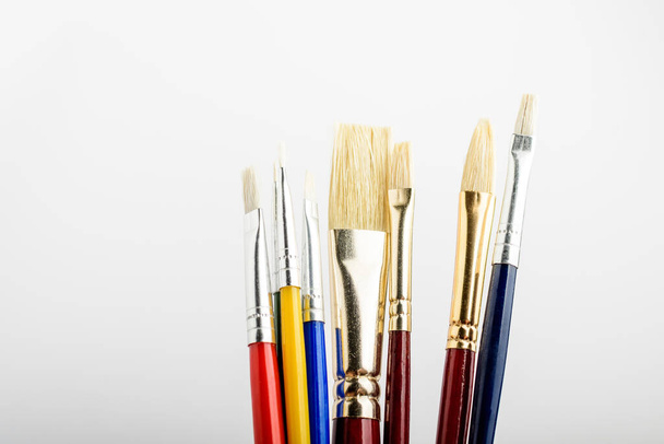 Many professional artist paintbrushes displayed vertically isolated on a white studio paper, photographed with soft focus - 写真・画像