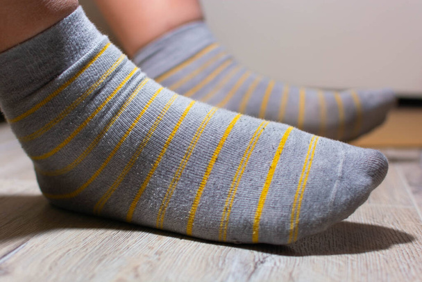 Gestreifte graue Socken an Männerbeinen. Gelbe Streifen auf Grau - Foto, Bild