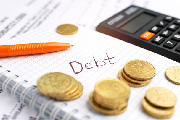 Debt concept. Close-up coins, pen, calculator at notebook. - Foto, Imagem