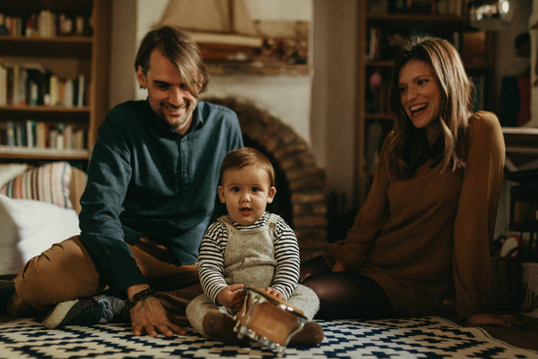 Young happy couple staying at home with their baby son sitting on the living room floor. - Foto, Imagen
