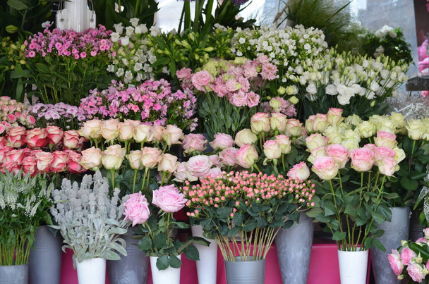 Mieszane letnie kwiaty wyświetlane przed kwiaciarnią, delikatne białe, różowe i czerwone róże i inne dekoracyjne rośliny wewnątrz fotografowane z miękkim ostrością - Zdjęcie, obraz