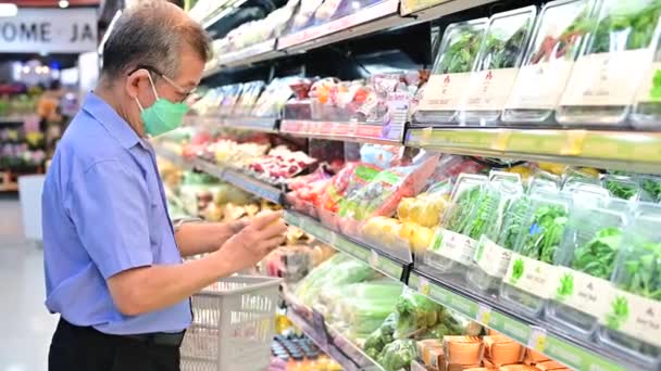 4K Senior man in mask escolhe legumes no supermercado
 - Filmagem, Vídeo