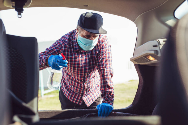 Man with mask disinfecting inside car.Prevent infection of Covid-19 virus. - Photo, image