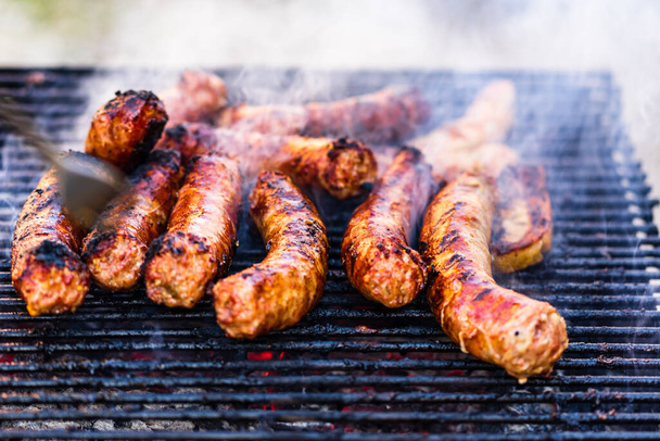 Worstjes gegrild op een houtskoolbarbecue. Top uitzicht op smakelijke barbecue, food concept, eten op grill en detail van worstjes op de grill - Foto, afbeelding