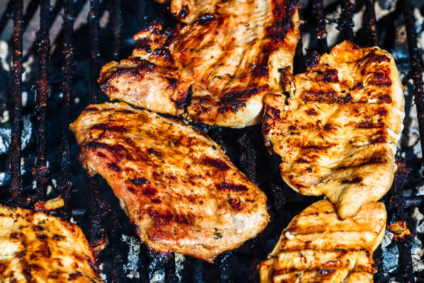 Κοτόπουλο και χοιρινό φιλέτο ψημένο σε κάρβουνο. Πάνω άποψη του κάμπινγκ νόστιμο μπάρμπεκιου, έννοια των τροφίμων, τα τρόφιμα στη σχάρα και τη λεπτομέρεια των τροφίμων στη σχάρα - Φωτογραφία, εικόνα