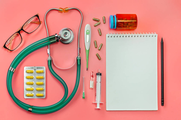 Concept, of medical equipment, flat lay top view. A stethoscope and notepad with pencil and medicine on a pink background. Health checkup or health insurance lung diagnosis, coronavirus, diagnosis of pneumonia. Cardiology doctor equipment. Medical he - Photo, Image