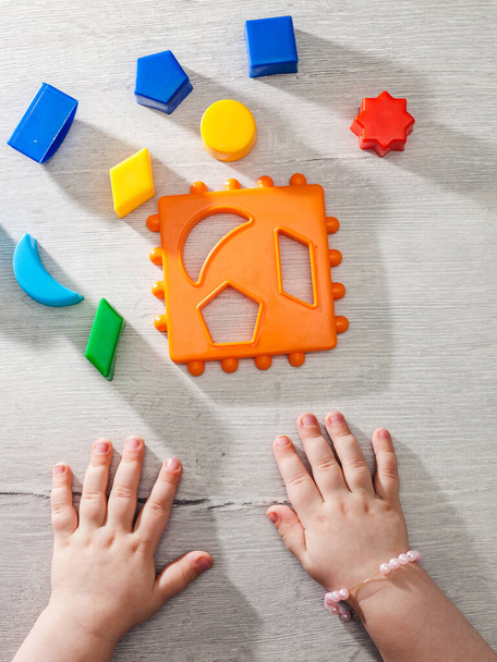 The child collects a sorter. Educational logic toys for kid's. Children's hands close-up. Montessori Games for Child Development. Vertical orientation - Foto, imagen