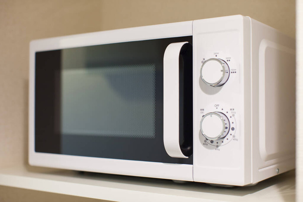 Weiße Mikrowelle mit nur einfachen Funktionen in der Küche im Haus platziert - Foto, Bild