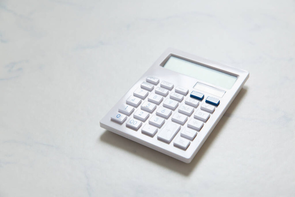 White calculator placed on a table made of white marble - Foto, Imagen