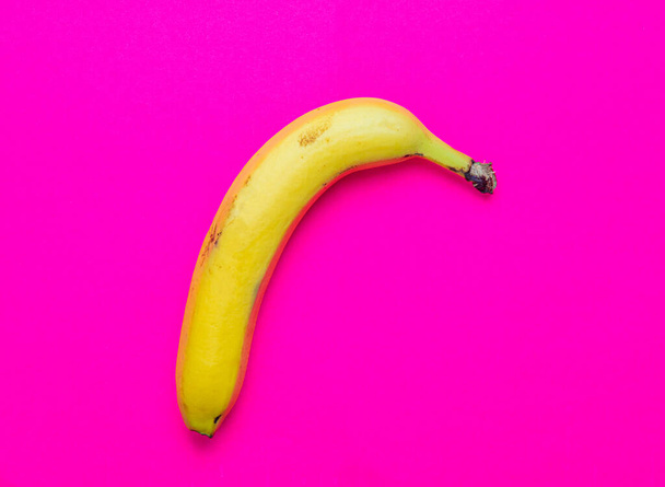 Colorful fruit of fresh yellow bananas on a pink background. Top view - Foto, Imagem