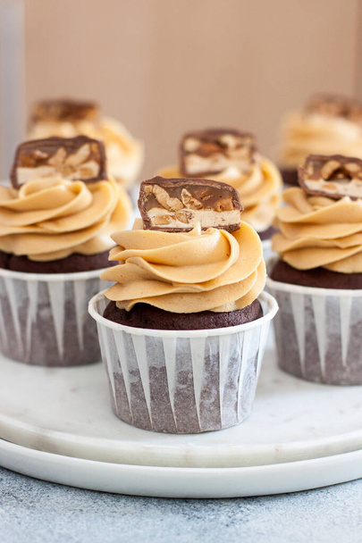 Homemade chocolate dough cupcakes with peanut butter frosting and snickers bites. Selective focus - Foto, Imagem