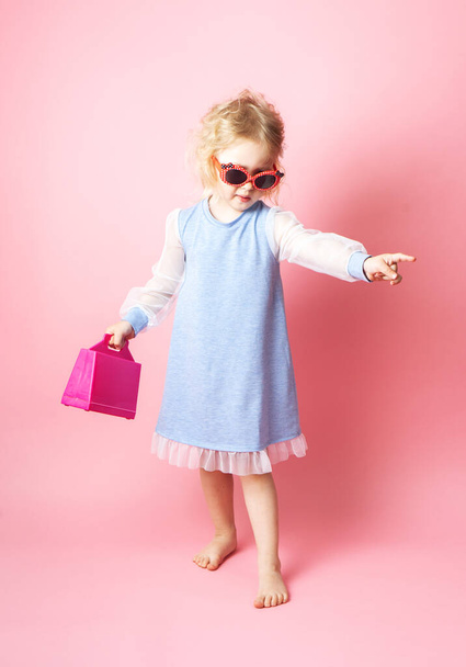 Little girl child in sunglasses with a pink redicle. - Foto, Bild